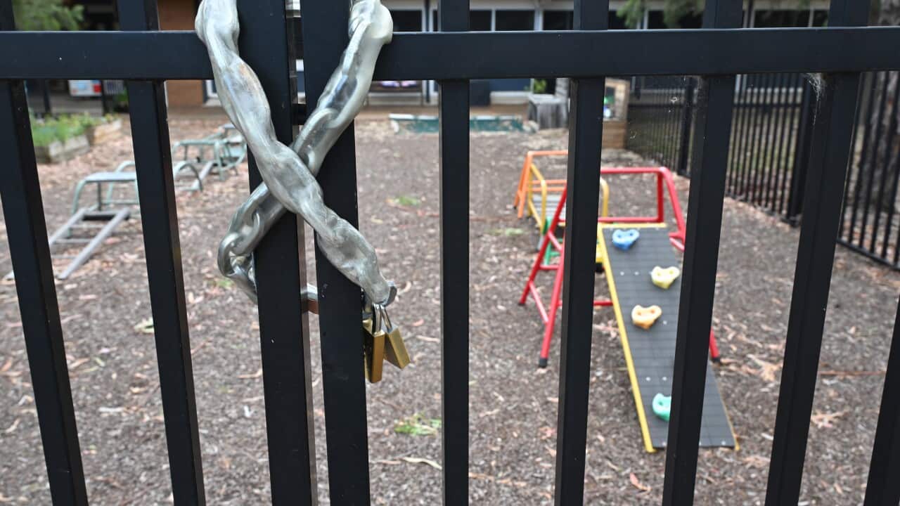 A gate with a chain and padlock around it, in front of play equipment.