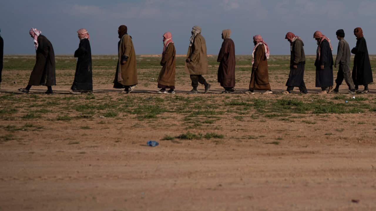 Men walk to a screening point after being evacuated out of Baghouz, eastern Syria