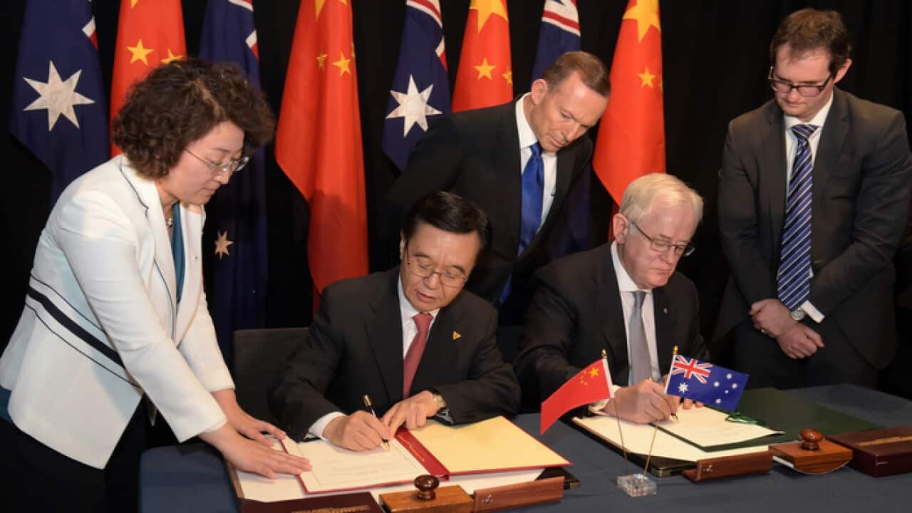 Australian Prime Minister Tony Abbott (centre) looks on as Chinese Minister of Commerce Dr Gao Hucheng (left) and Australian Minister for Trade Andrew Robb sign the Free Trade Agreement AAP