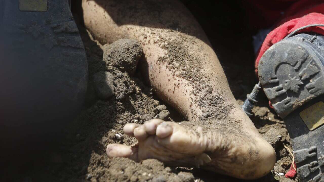 A body is pulled from under the dirt