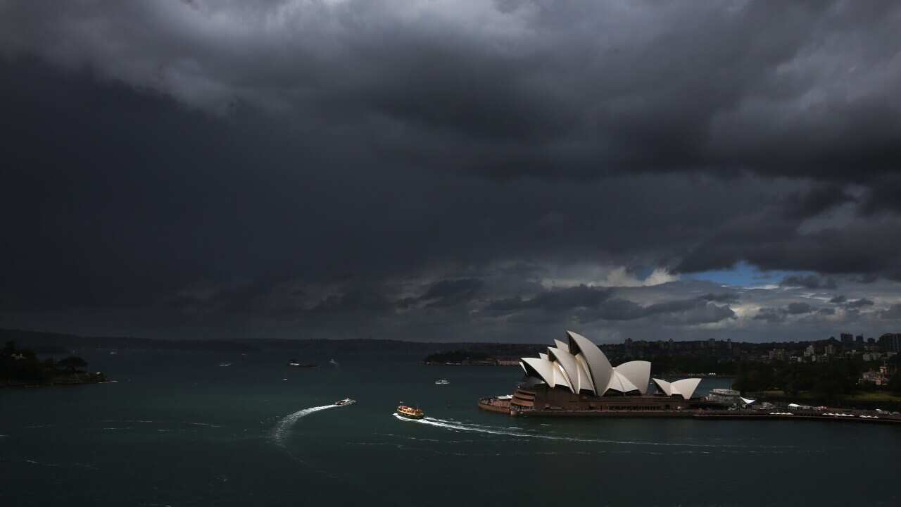 Sydney Harbour and the Opera House under storm clouds with several ferries visible in the water