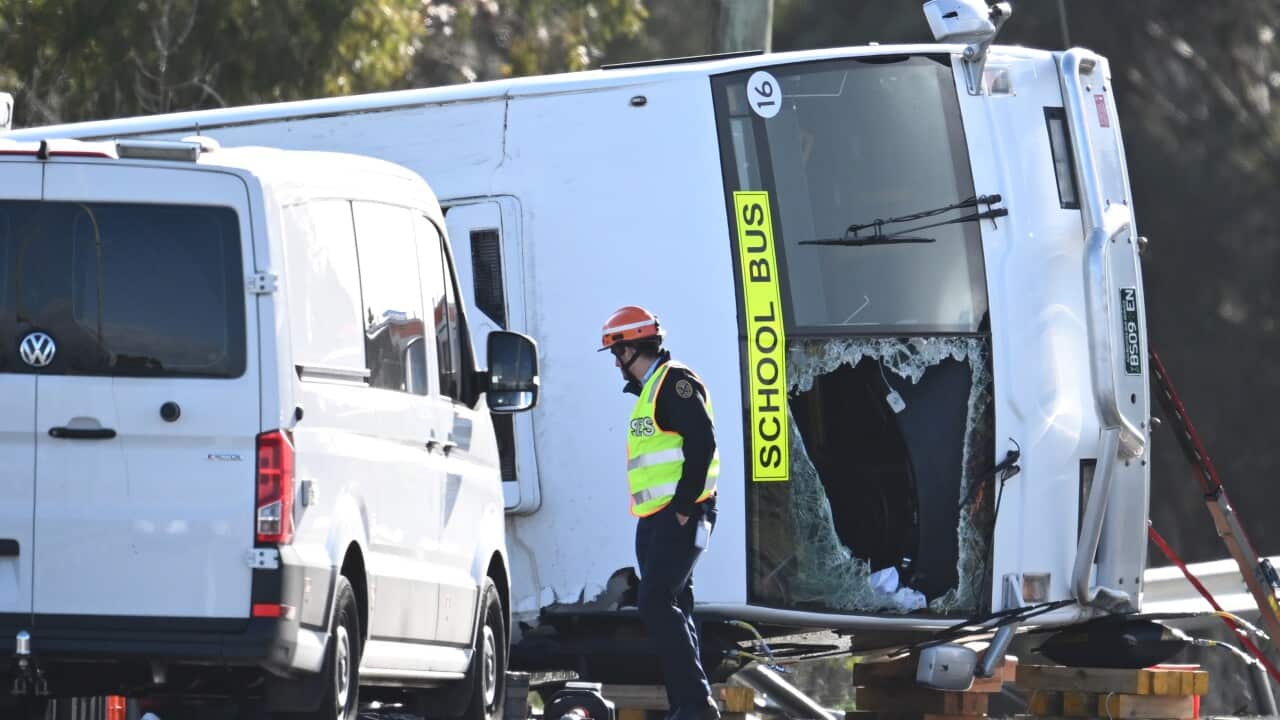 A rescue worker surveys a bus that rolled over and crashed in Victoria.