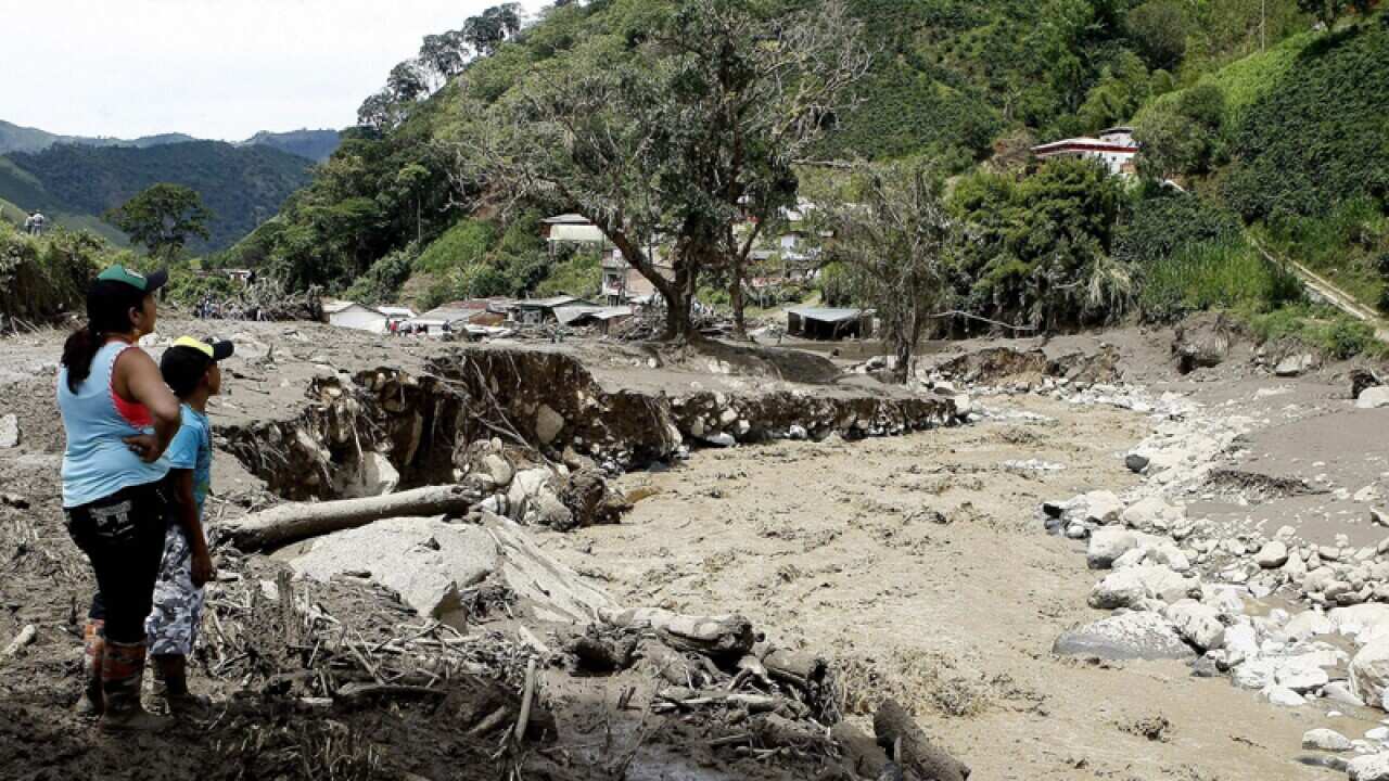 A woman and boy look at the damaged caused by flooding