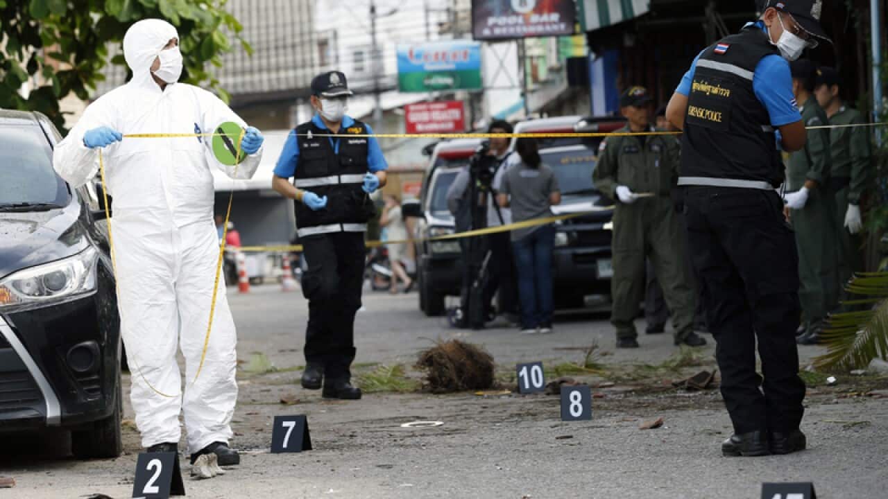 Thai forensic police officers inspect the scene of a bomb blast