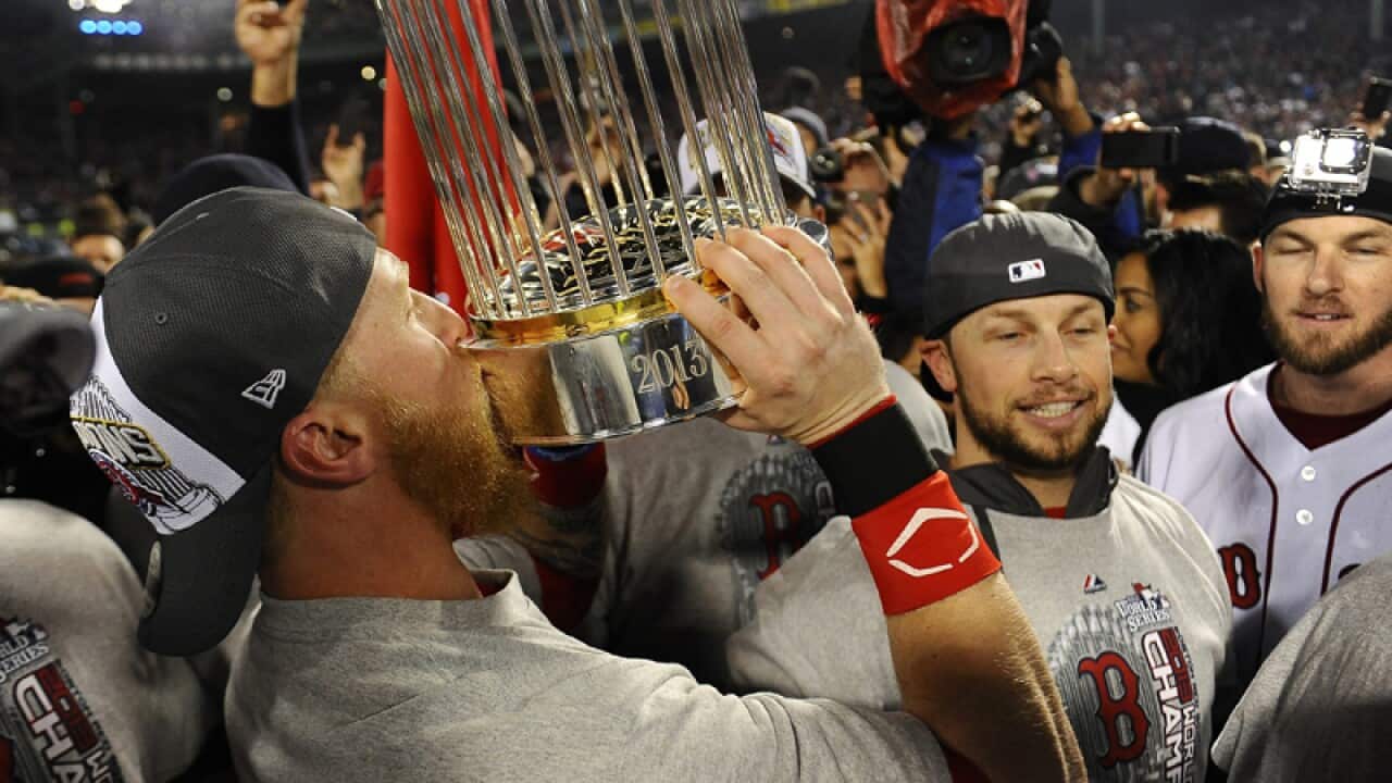 Boston Red Sox player Mike Carp (l) kisses the World Series trophy