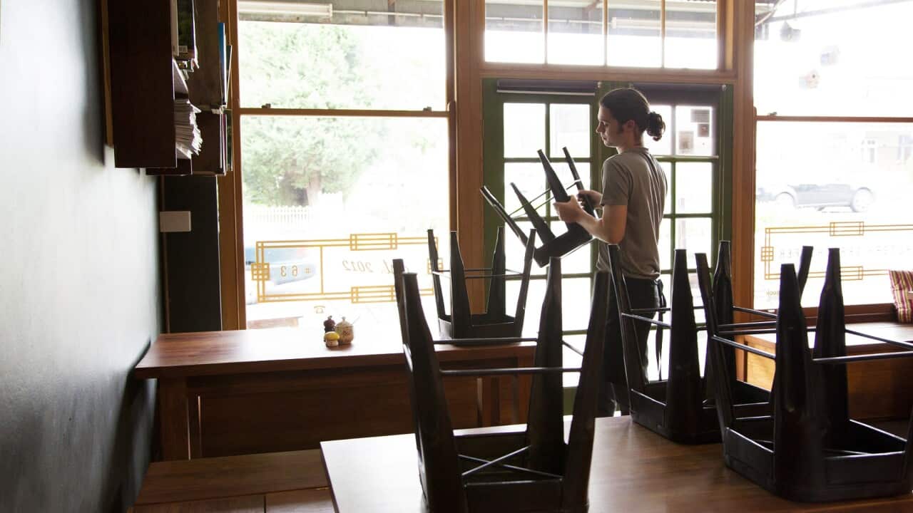 Waiter packing up cafe or restaurant chairs