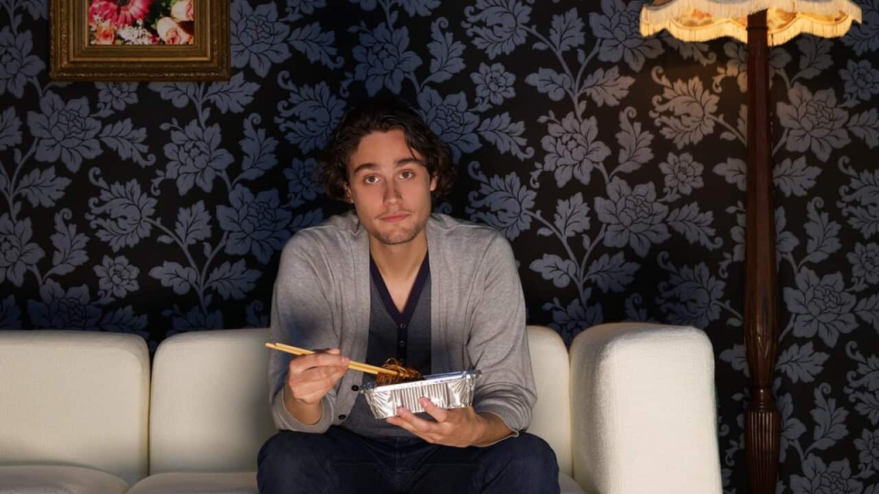 Young man sitting on sofa holding take out food
