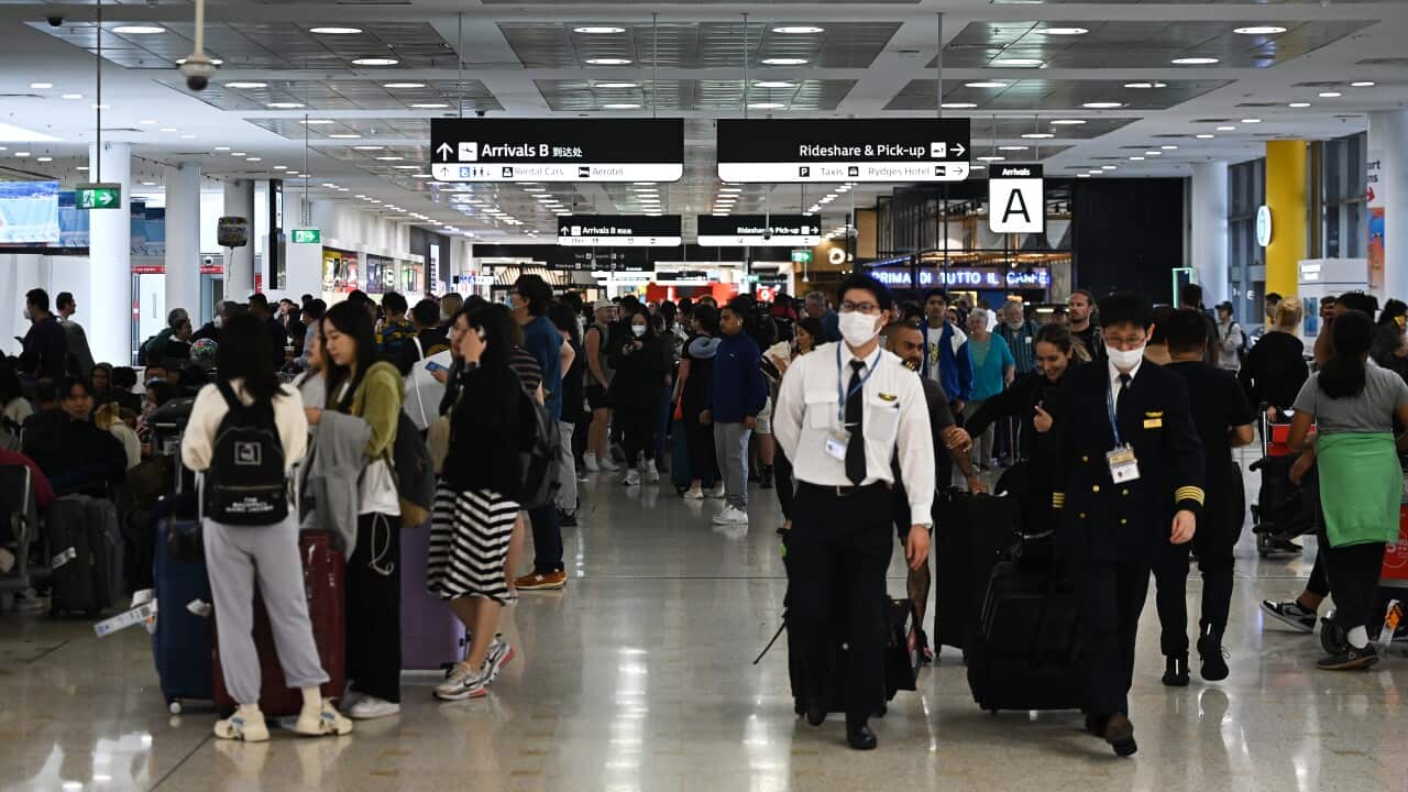 Travellers standing in an airport arrivals hall.