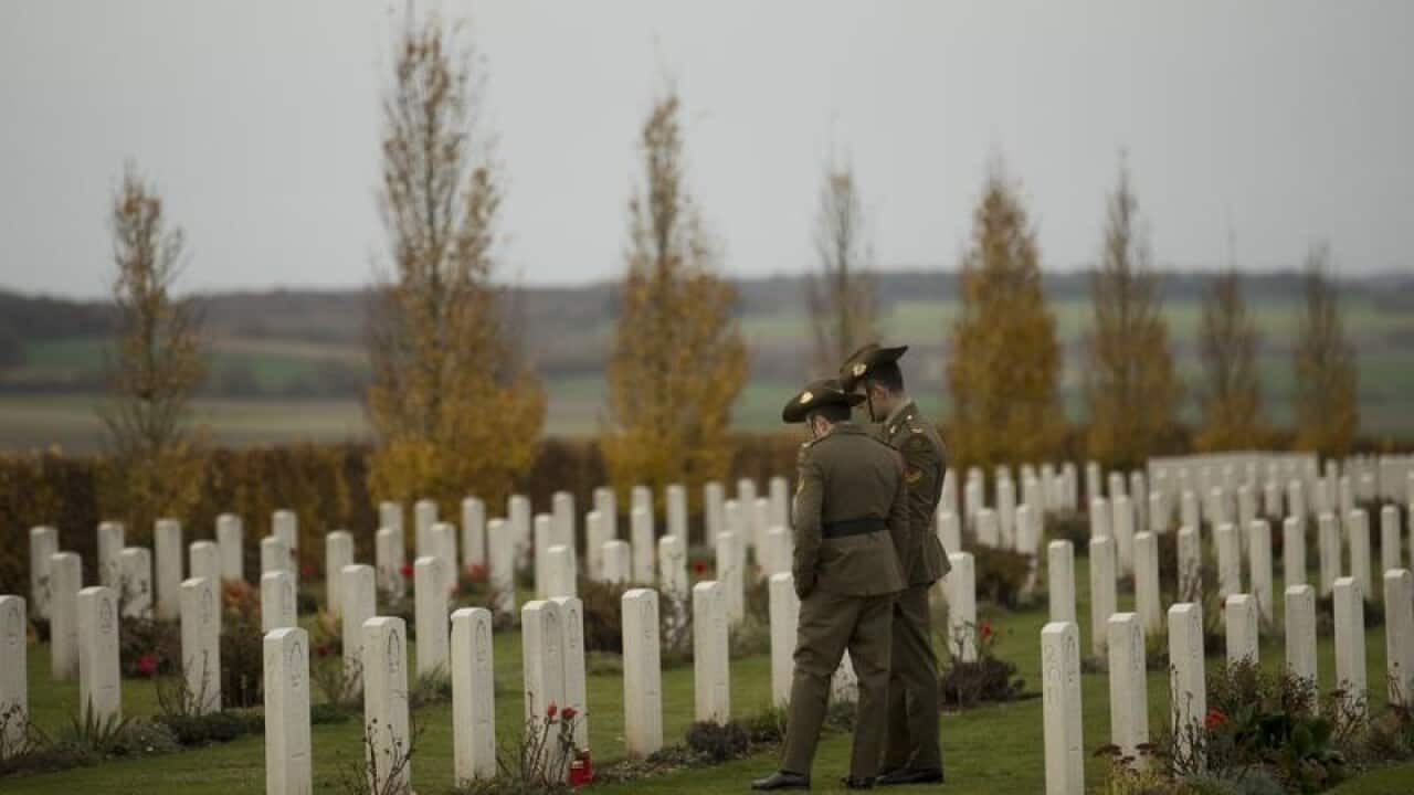 Two soldiers walk along the graves at Villers-Bretonneux
