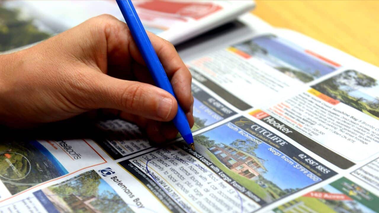 Checking out real estate advertising in a newspaper in Brisbane