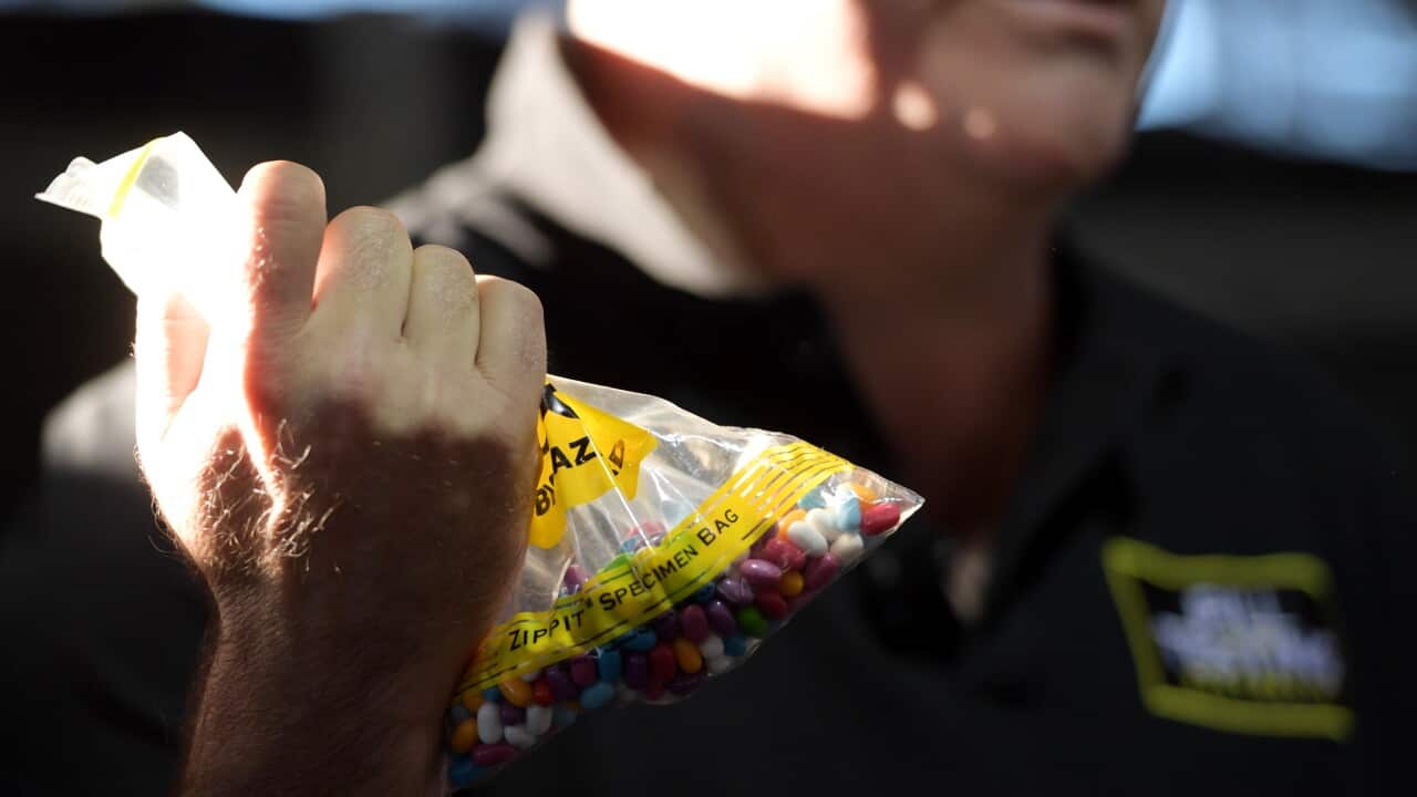 An officer holding a specimen bag filled with tablets