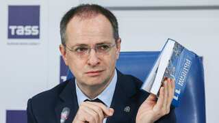 Russian presidential aide holding new history textbooks that praise the country's invasion of Ukraine.