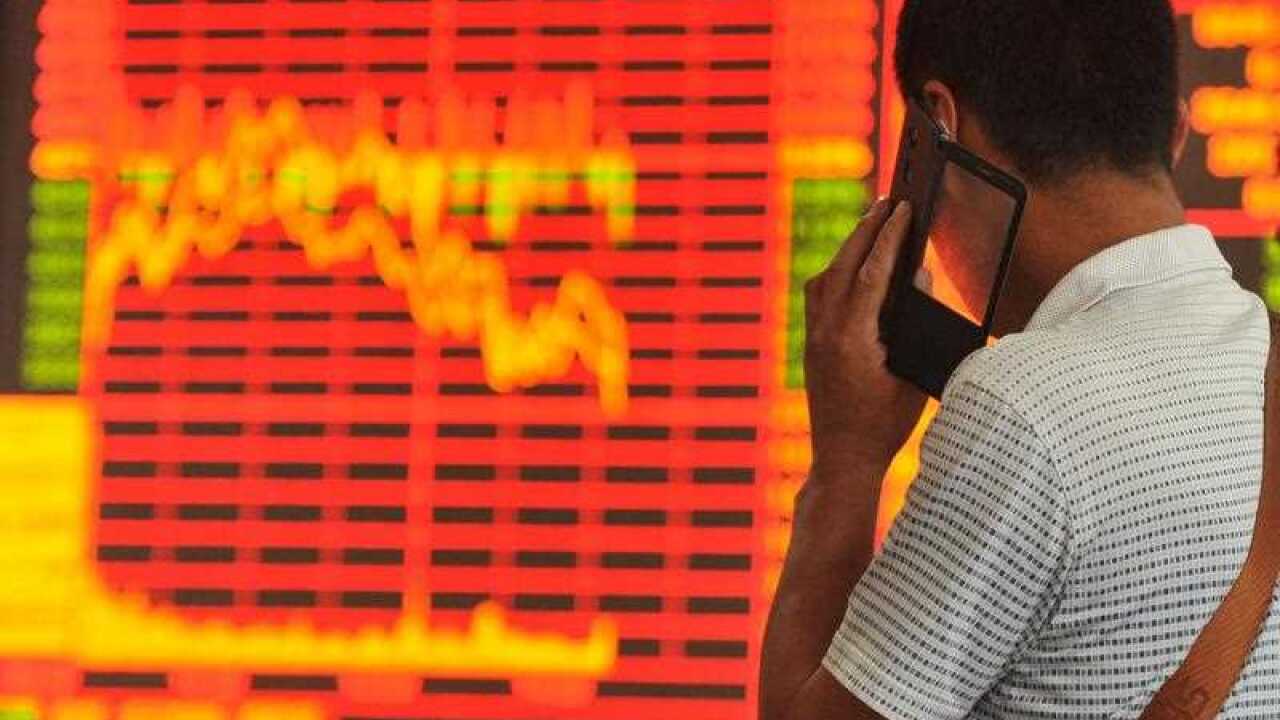 A Chinese investor talks on his mobile phone as he looks at the Shanghai Composite Index at a stock brokerage house in Fuyang city