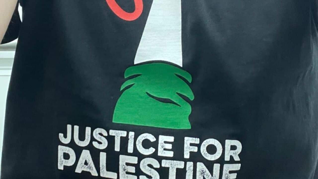 A black T-shirt with a picture of a hand raising a key aloft and “Justice for Palestine“ written on it.