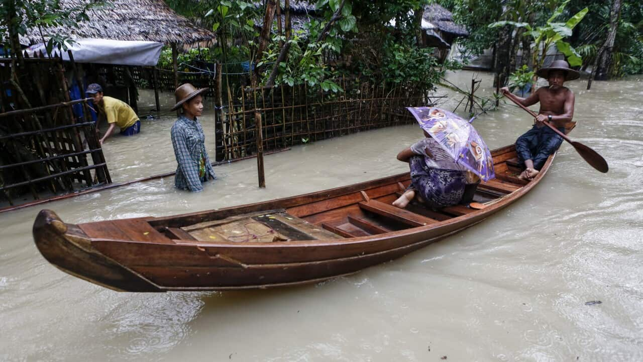 A man rows a boat with passenger as they pass through a flooded road at Kyein Chaung village of Kangyee Daunk township in Ayeyarwady Region, Myanmar.