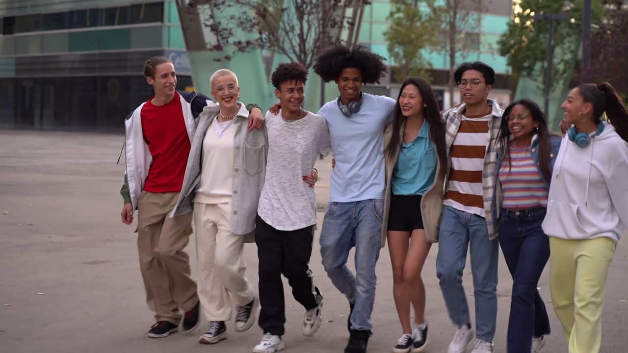 multiethnic-group-of-young-happy-friends-walking-down-the-street-holding-each-other-af-SBI-351592046.jpg