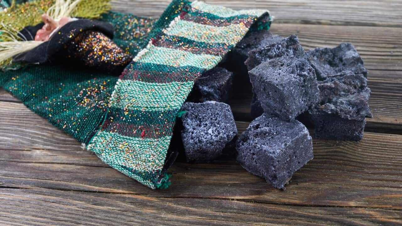 Befana sock with sweet coal and candy on wooden background. Italian Epiphany day tradition.