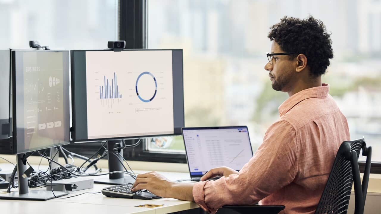 A man sitting at a desk and doing work on a computer