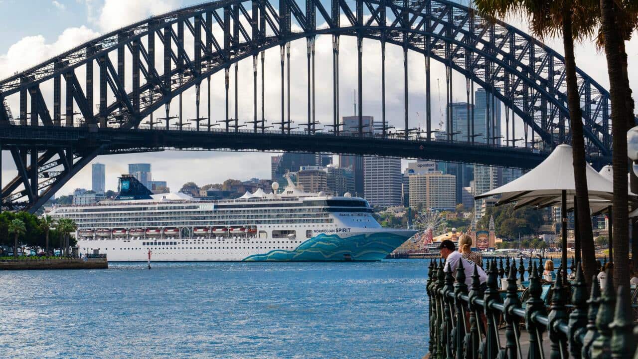 A cruise ship passing under the Sydney Harbour Bridge.