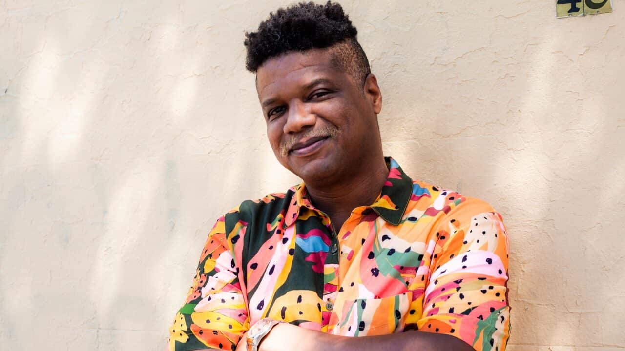 Afro-Brazilian Latinx writer and poet Guido Melo standing against a wall