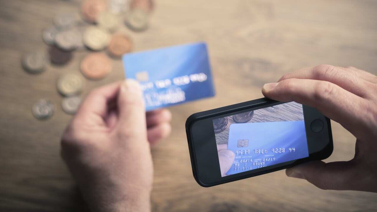 Mans hands photographing credit card using smartphone