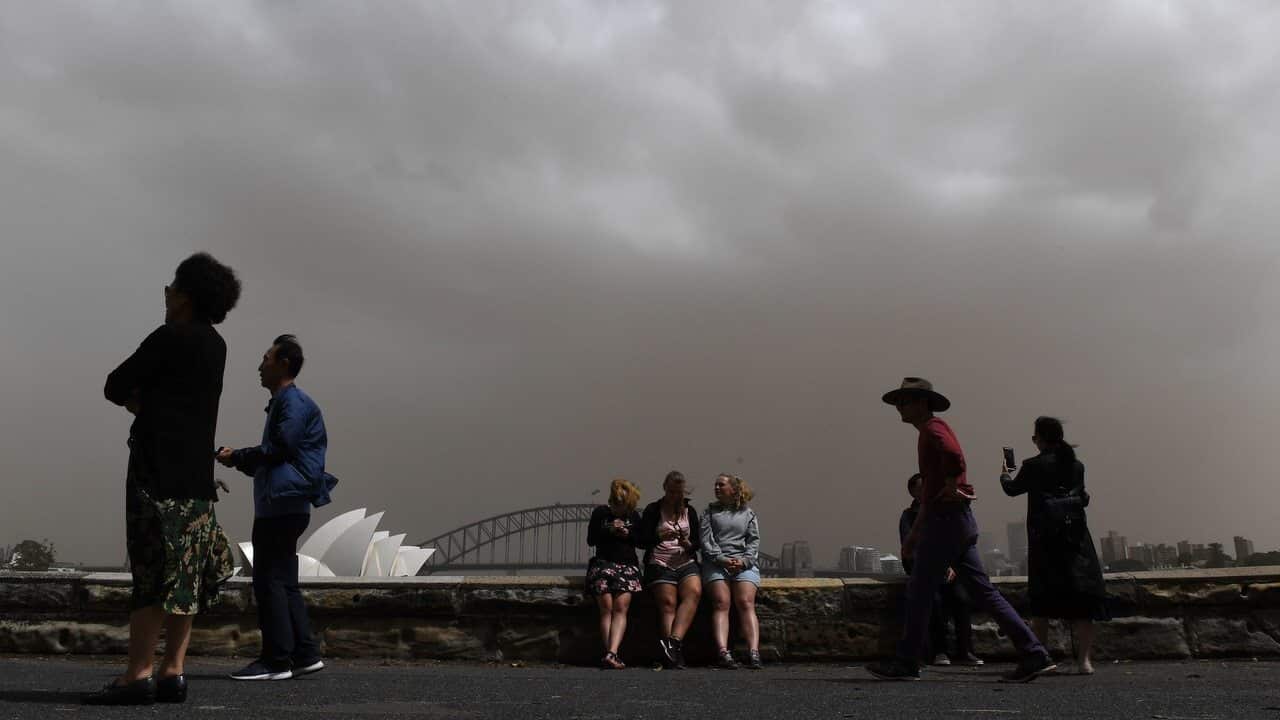 Chinese tourists take photographs as a dust storm descends on Sydney.