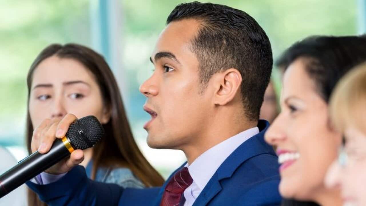 Concerned Hispanic citizen asks political candidate a question during meeting