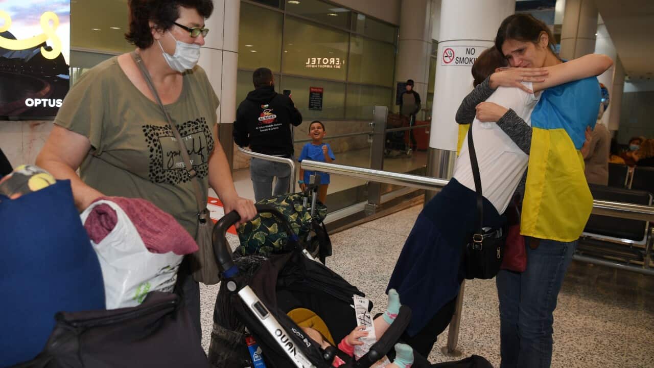 Ukrainian-Australian Olha Lyeskakova (draped in Ukrainian flag) gives an emotional welcome to her mother Olena, sister Iryna and young niece Oksana at Sydney International Airport in Sydney, Saturday, March 12, 2022