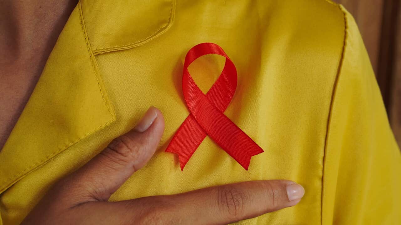 Red AIDS Awareness Ribbon on Woman’s Chest