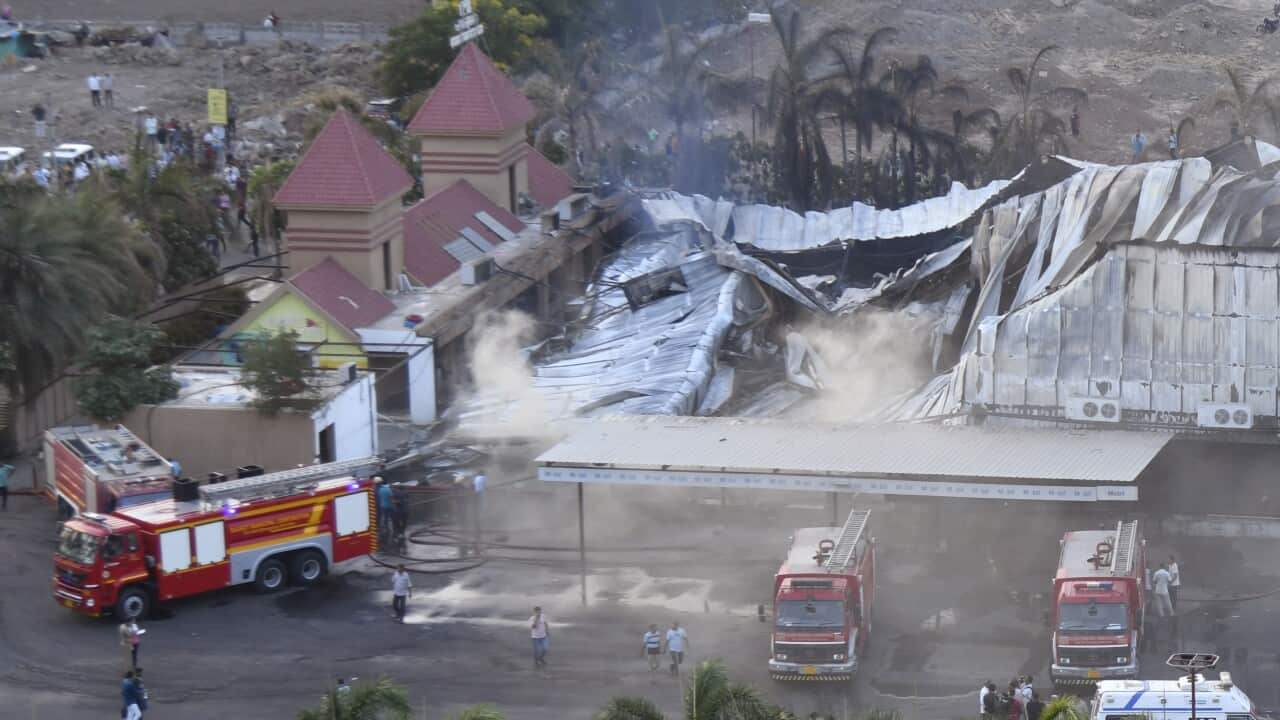 The ruins of a building after a fire with firetrucks in front of it