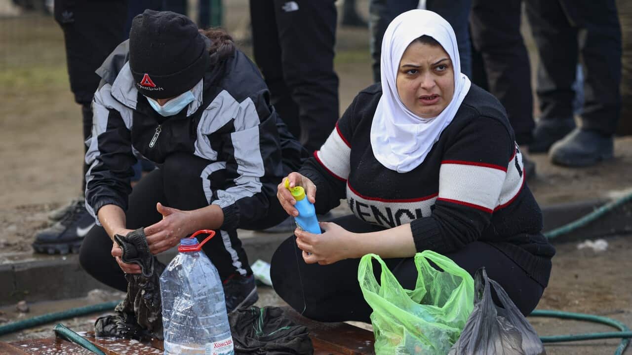 A couple washes clothes in a transport and logistics centre at the Belarusian-Polish border