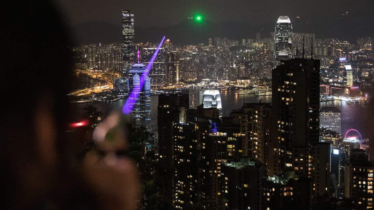 A pro-democracy protester points a high powered laser pointer at other protesters who had gathered on Lion Rock.