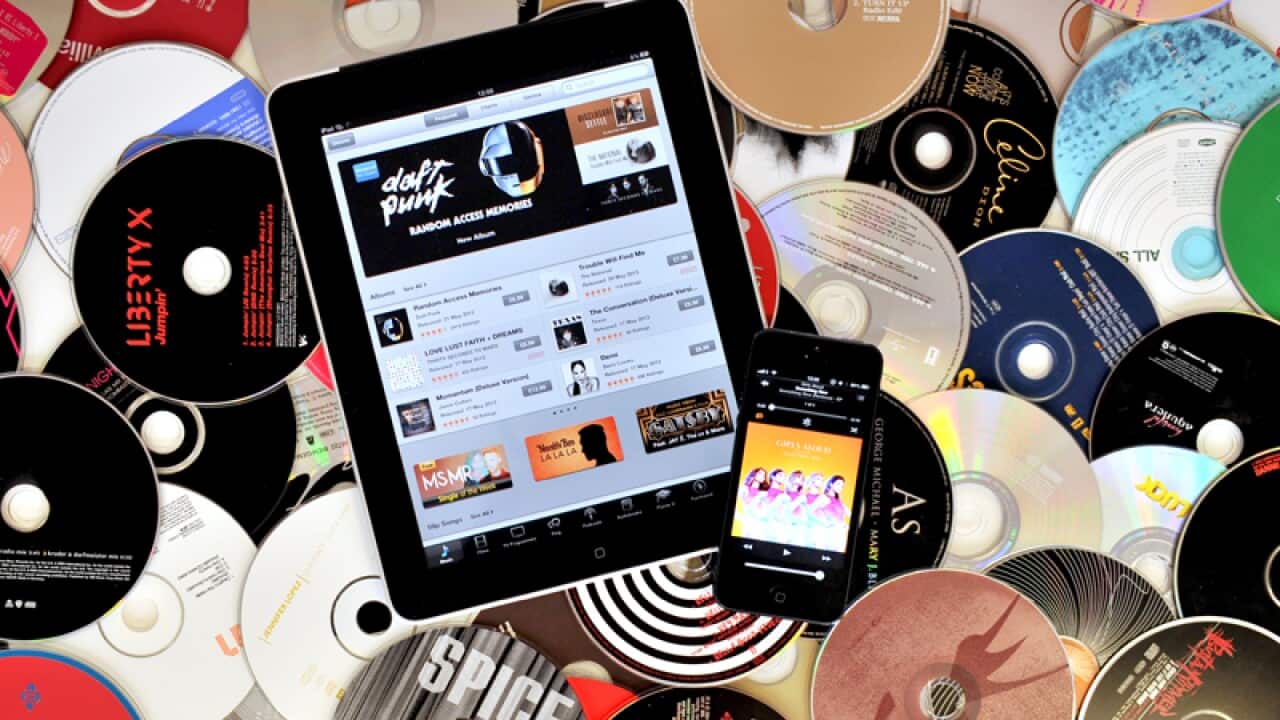 View of an iPad and iPhone resting on top of a compilation of CD