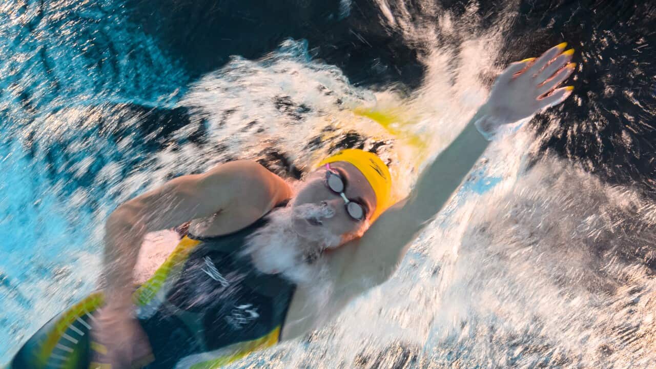 A woman streams underwater in an Australian Olympic outfit