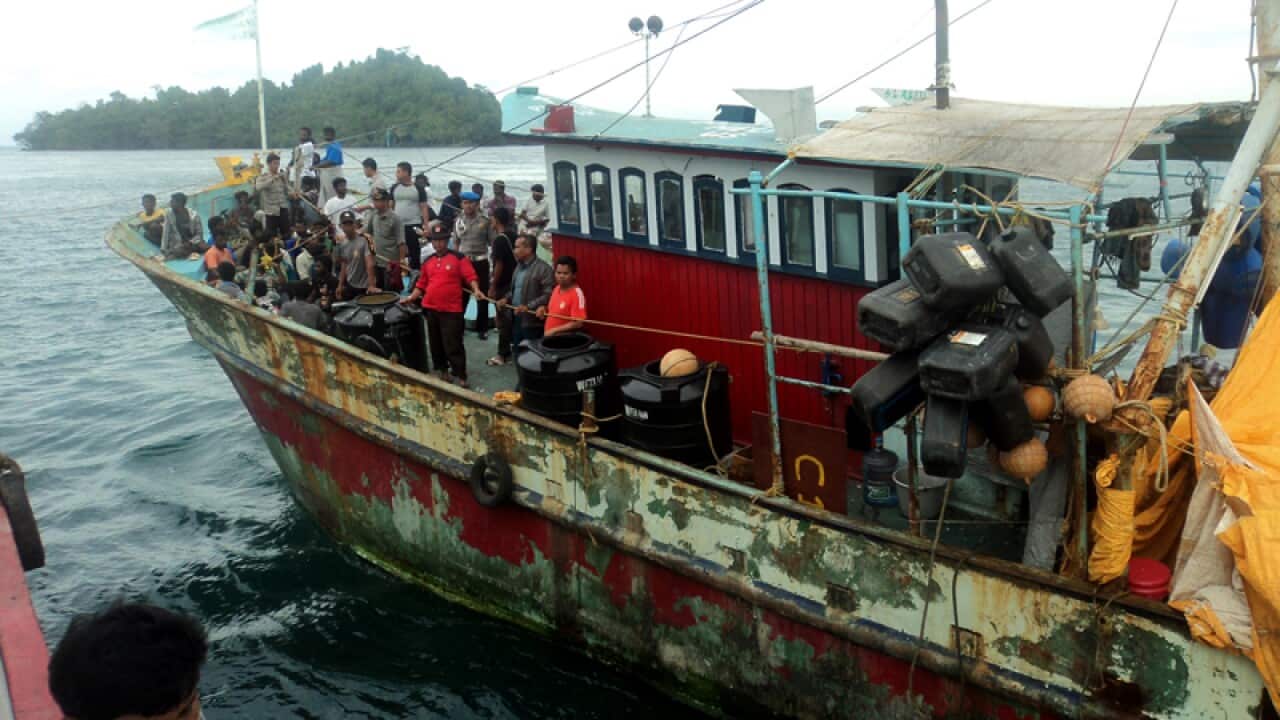 Indonesian police stand guard on a boat carrying asylum seekers