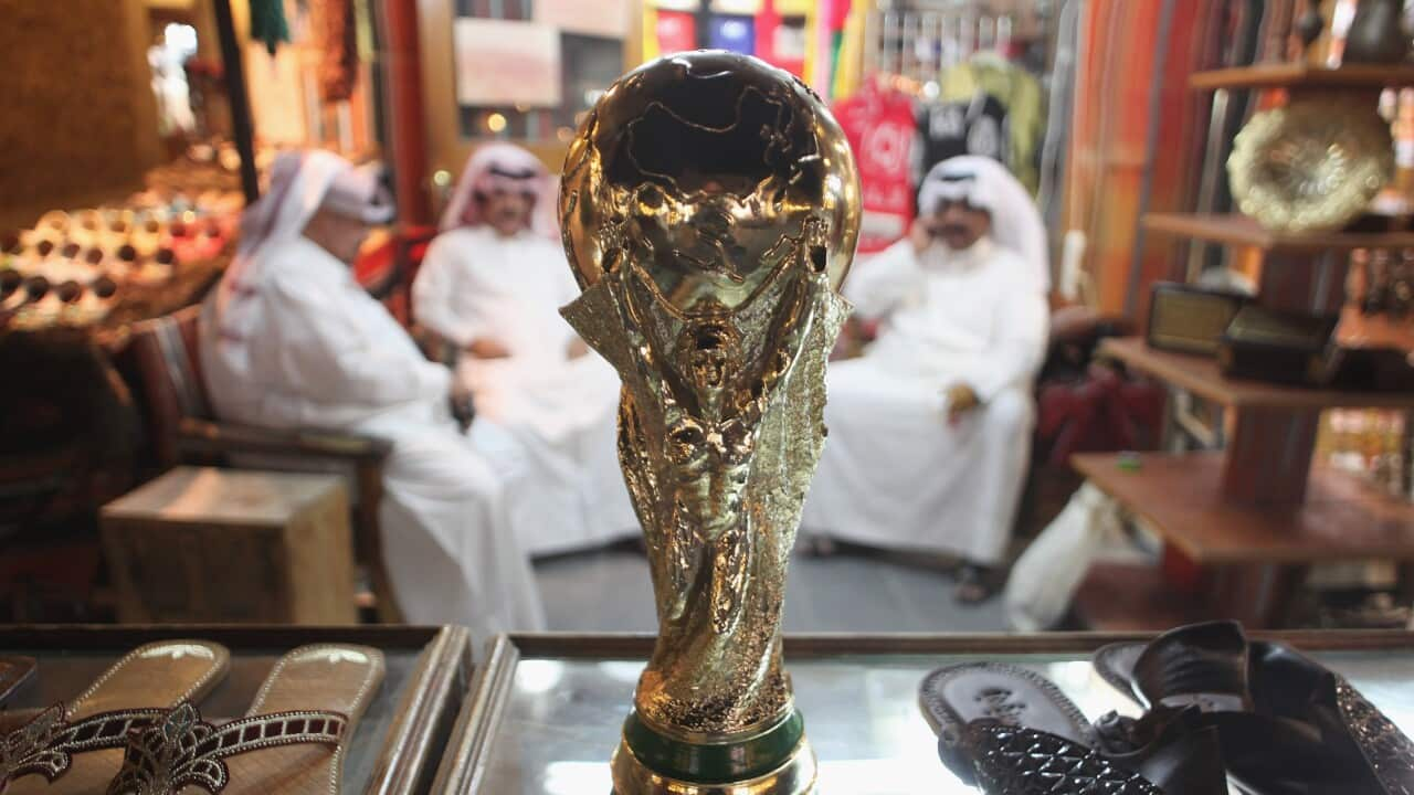 Arab men sit at a shoemaker's stall with a replica of the FIFA World Cup trophy in the Souq Waqif traditional market on October 24, 2011 in Doha, Qatar. 