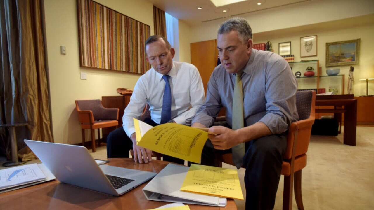 Prime Minister Tony Abbott and Treasurer Joe Hockey pose for pictures as they look through budget papers at Parliament House in Canberra, Tuesday, May 5, 2015. (AAP Image/Lukas Coch)