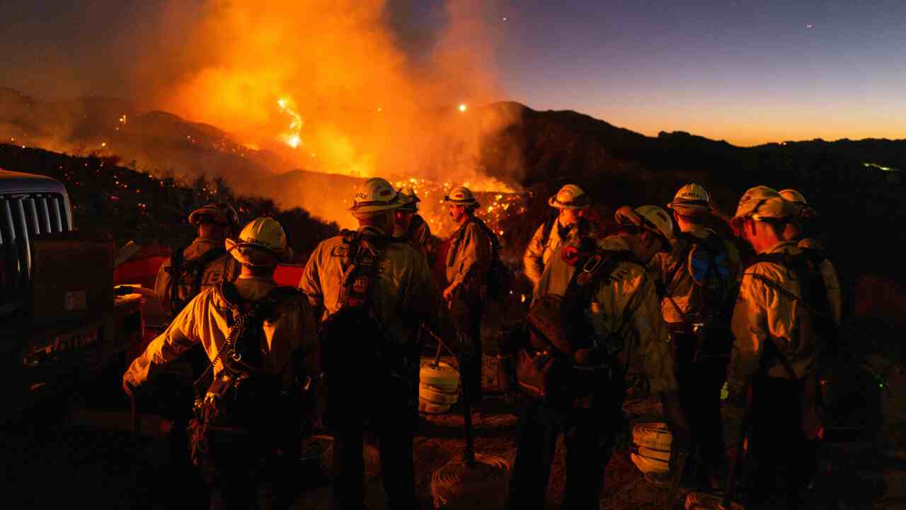 A group of firefighters stand in front of a fire