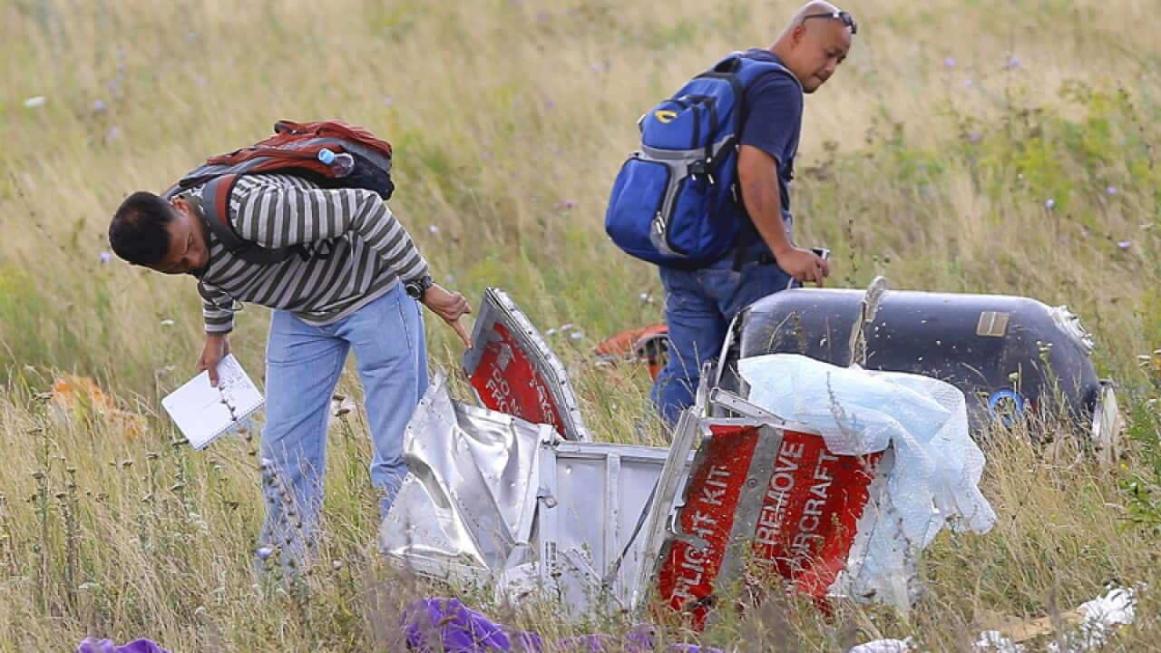 Malaysian experts check debris at the main crash site of flight MH17