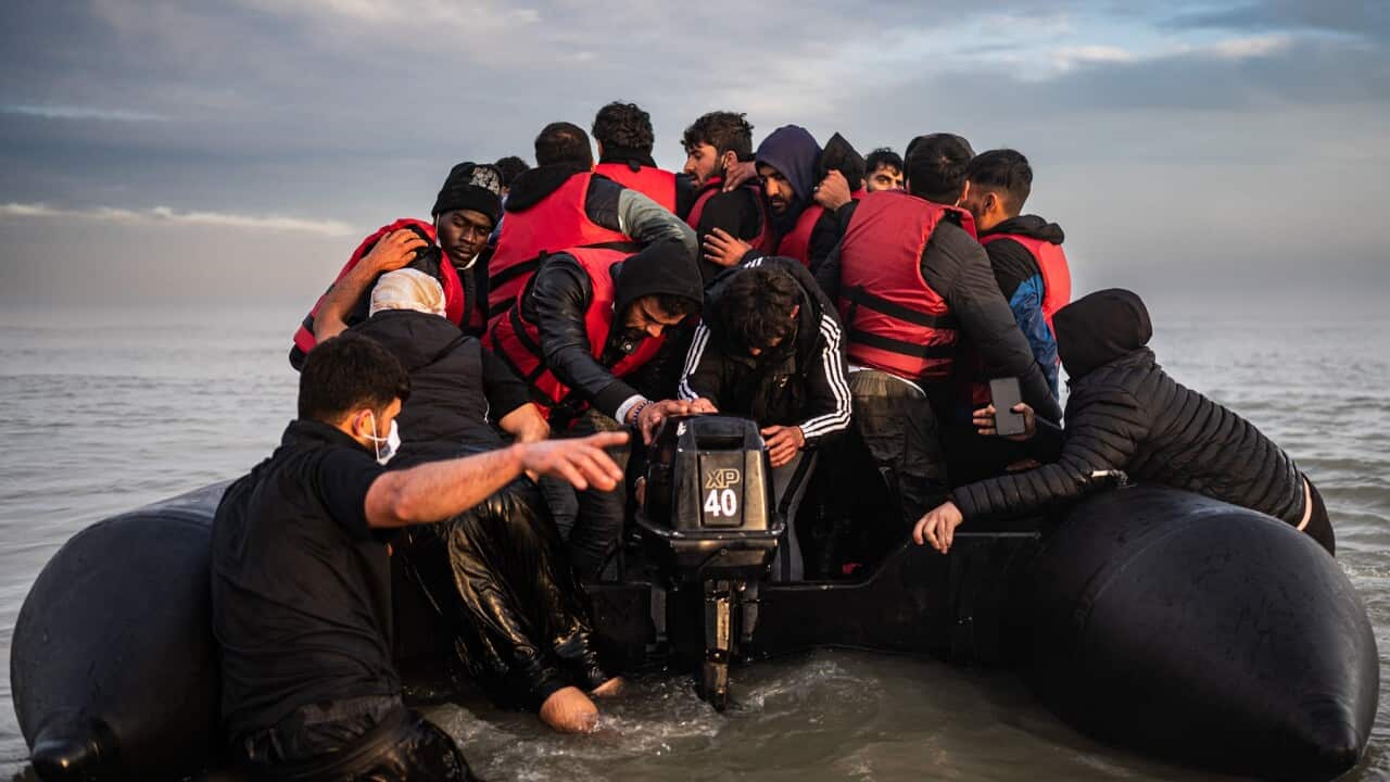 Migrants try to start an outboard engine after boarding a smuggler's boat on the beach of Gravelines, near Dunkirk, northern France