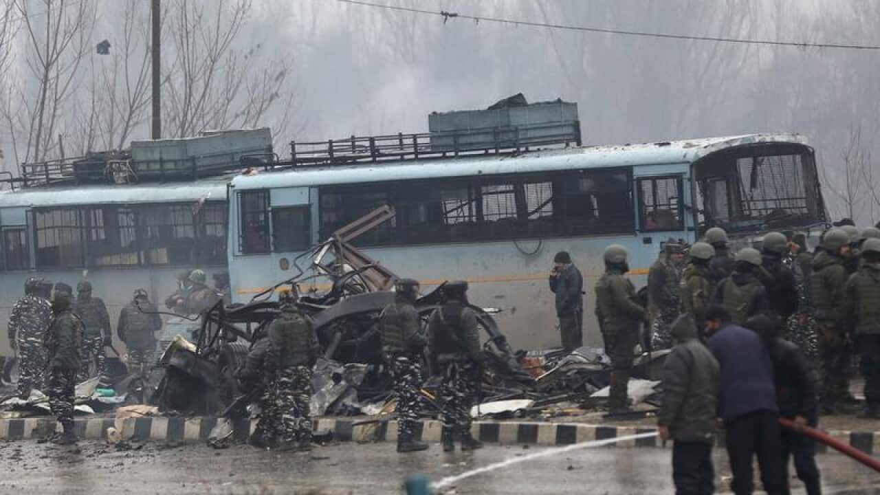 Security forces near the damaged vehicles in Kashmir.
