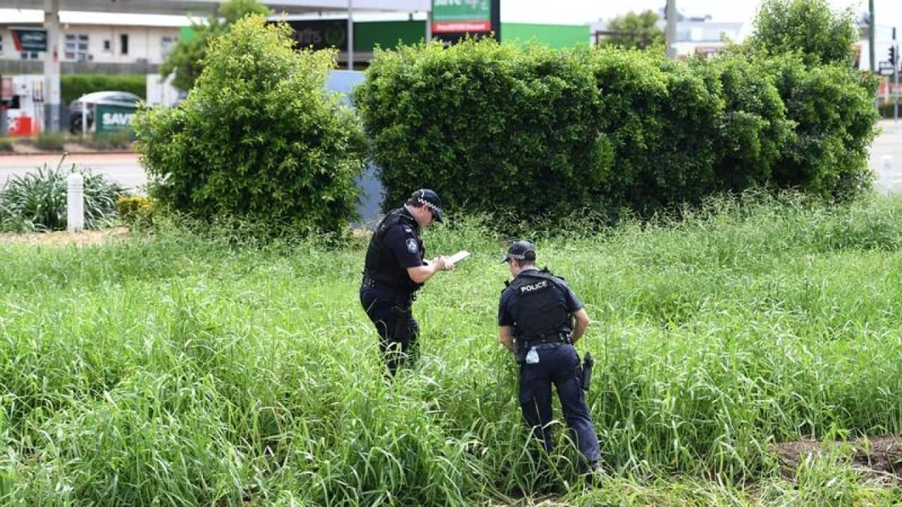 Police search the scene where two bodies were found in a drain.