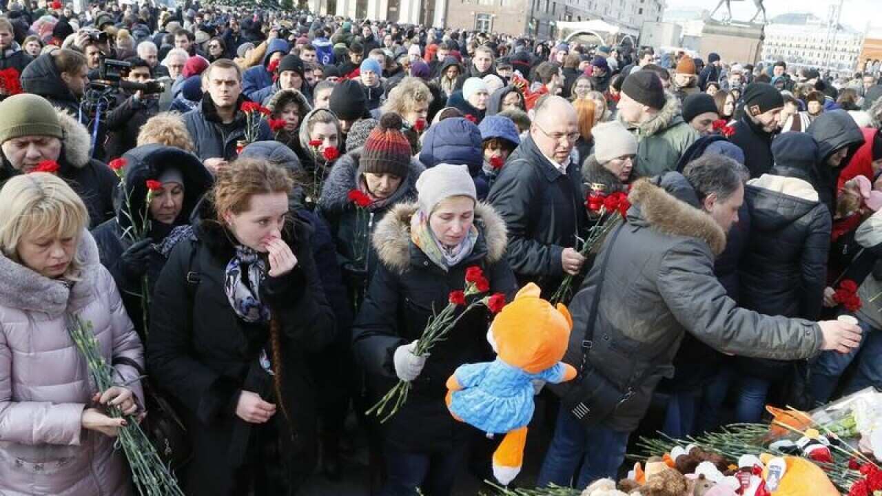 People lay gifts at a memorial for victims of a fire in Russia.