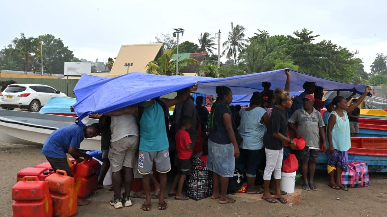 Solomon Islanders shelter from the rain while waiting to board small boats to vote in their provinces (AAP)