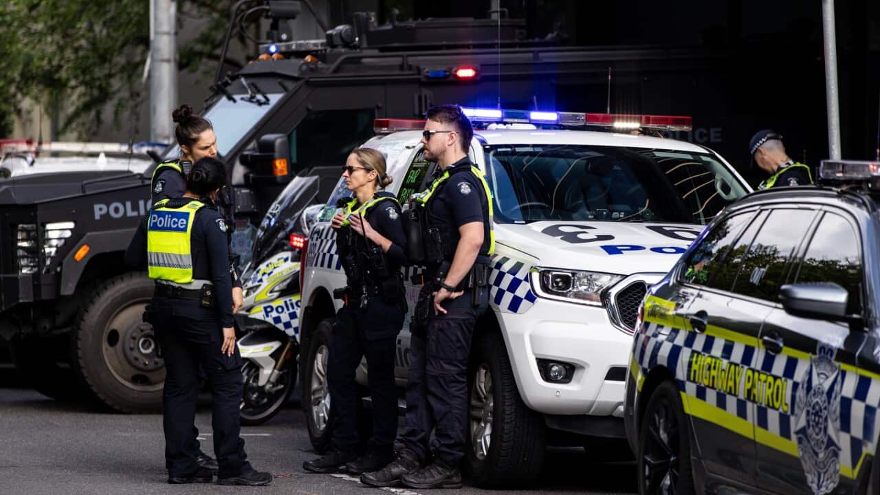 Police officers standing next to a police vehicle.