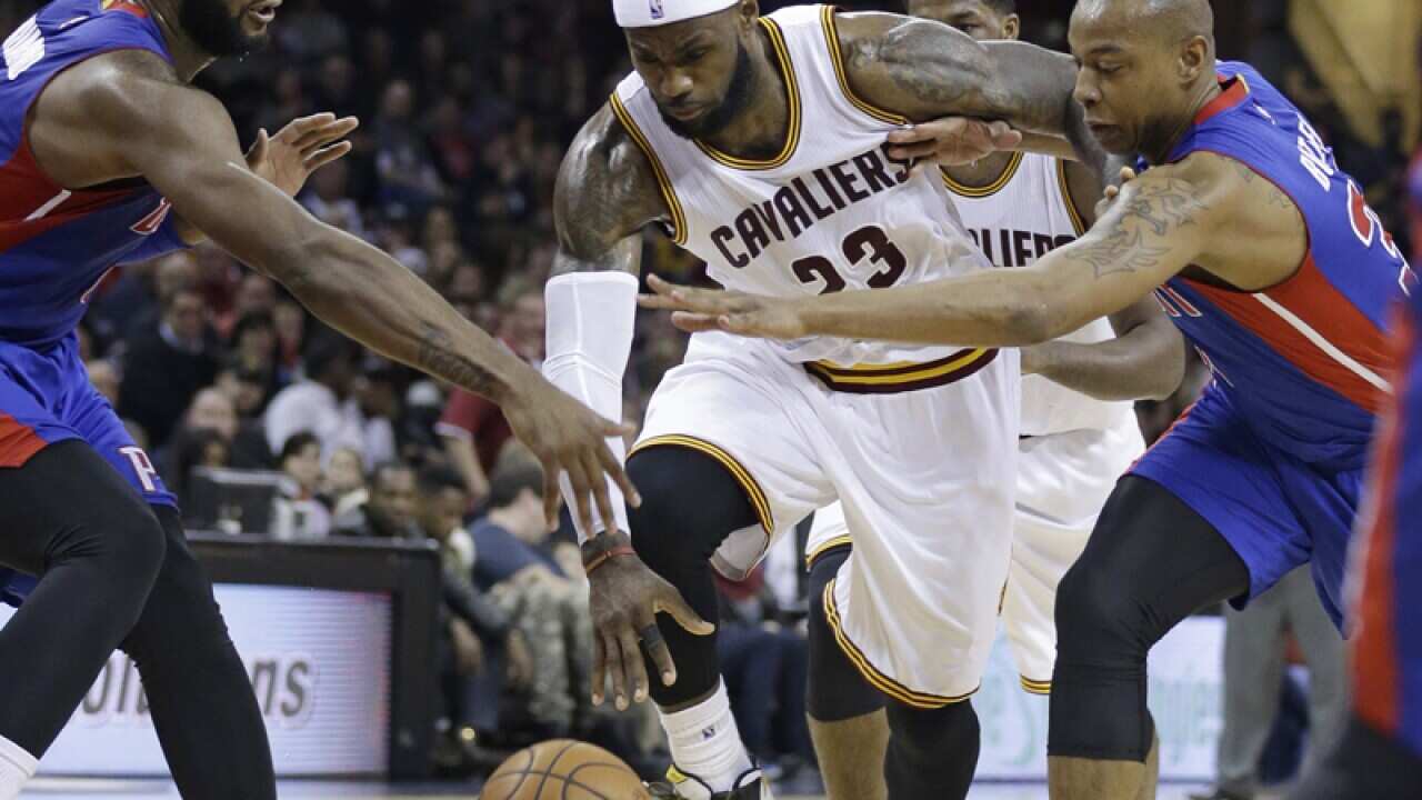 Cleveland's LeBron James (C)tries to squeeze between Detroit's players