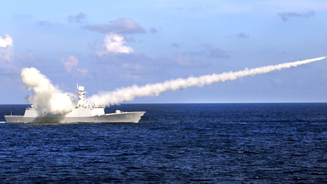 A chinese ship fires a missile leaving a trail of smoke.