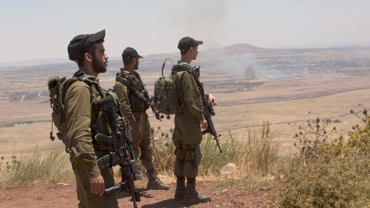 Israeli soldiers observe smoke rising from Syrian village as a result of fighting near the city of Quneitra, in the Golan Heights 