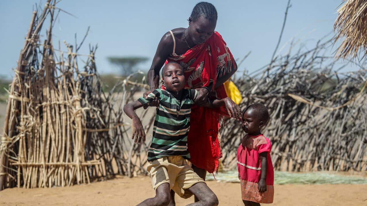 A mother helps her malnourished son stand after he collapsed near their hut in the village of Lomoputh in northern Kenya