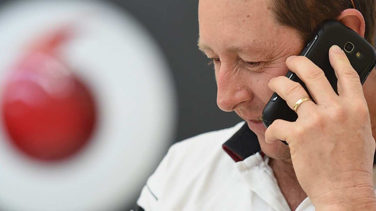 A man is seen using his phone outside a Vodafone store in Tweed Heads